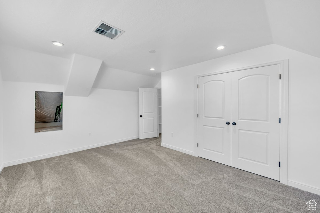 Bonus room featuring light colored carpet and lofted ceiling