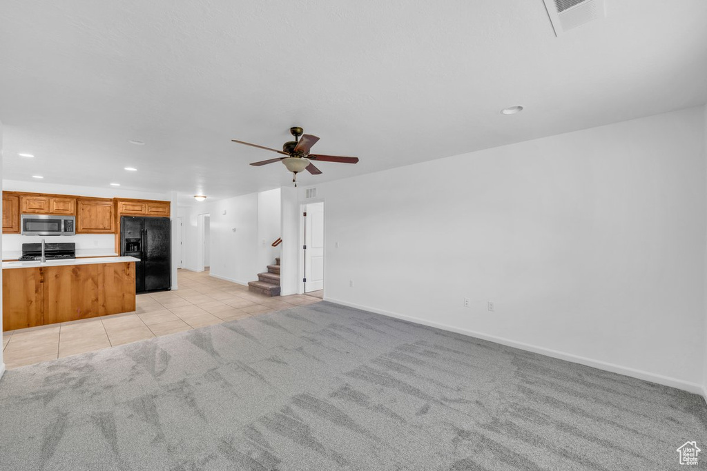 Unfurnished living room with light tile flooring and ceiling fan