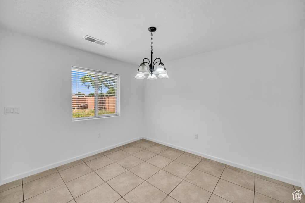 Unfurnished room with a chandelier and light tile floors