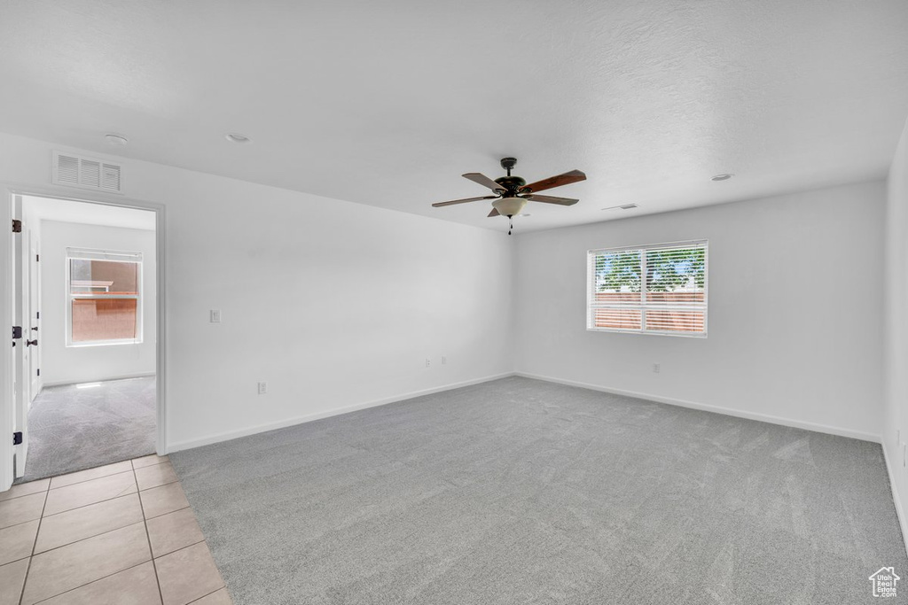 Empty room featuring ceiling fan and light tile floors