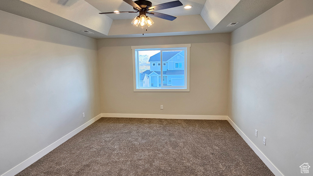 Carpeted spare room with ceiling fan and a tray ceiling