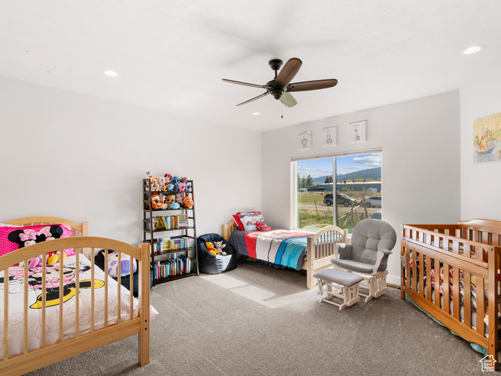 Bedroom featuring a crib, ceiling fan, and carpet floors