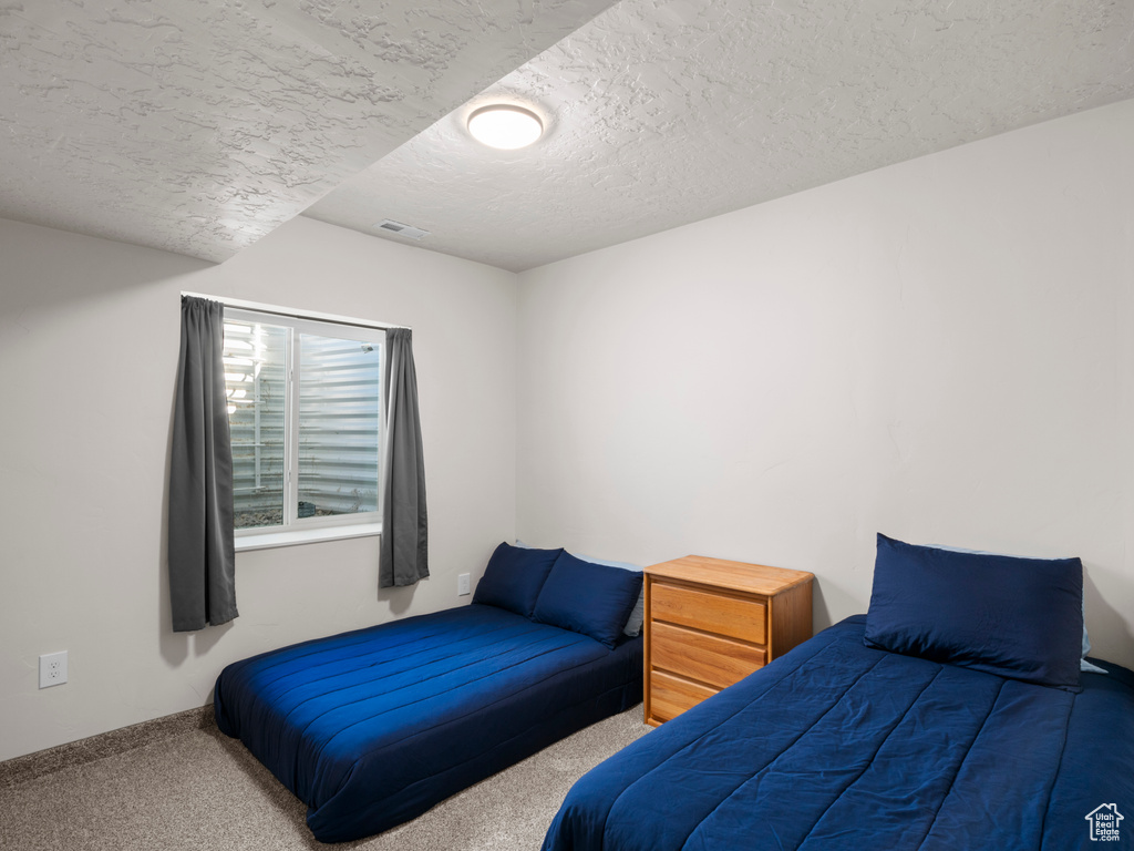 Bedroom with a textured ceiling and carpet flooring