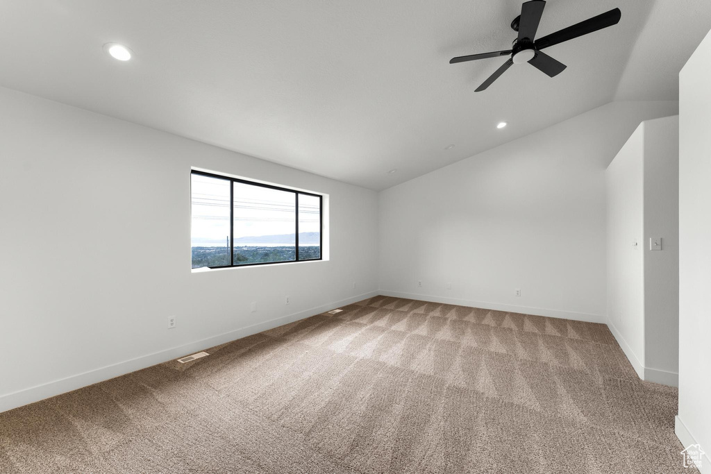 Unfurnished room featuring ceiling fan, vaulted ceiling, and light carpet