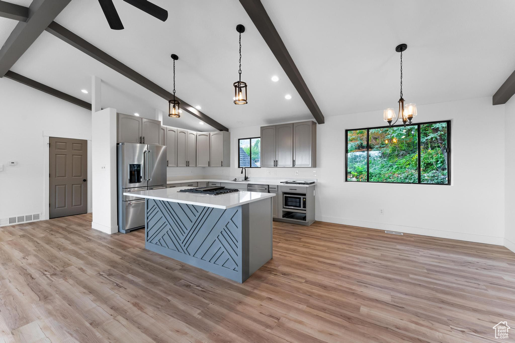 Kitchen featuring stainless steel appliances, hanging light fixtures, and light wood-type flooring