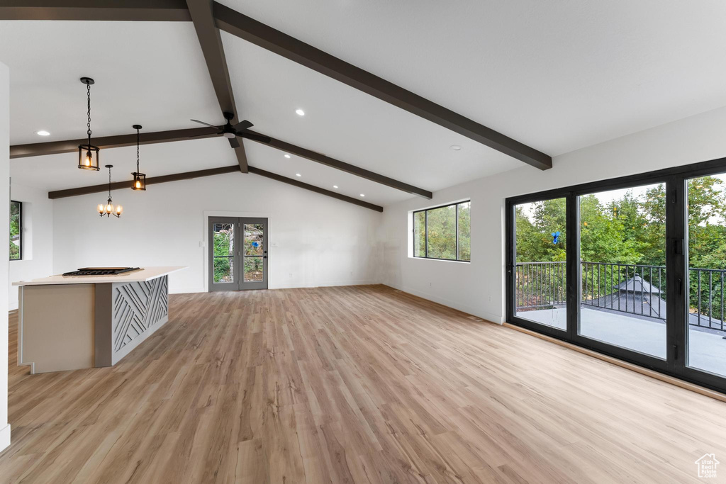 Unfurnished living room featuring light hardwood / wood-style floors, vaulted ceiling with beams, and a chandelier