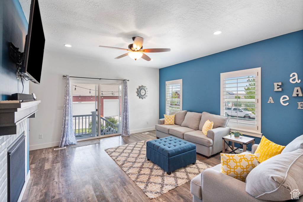 Living room featuring ceiling fan, hardwood / wood-style flooring, and a textured ceiling