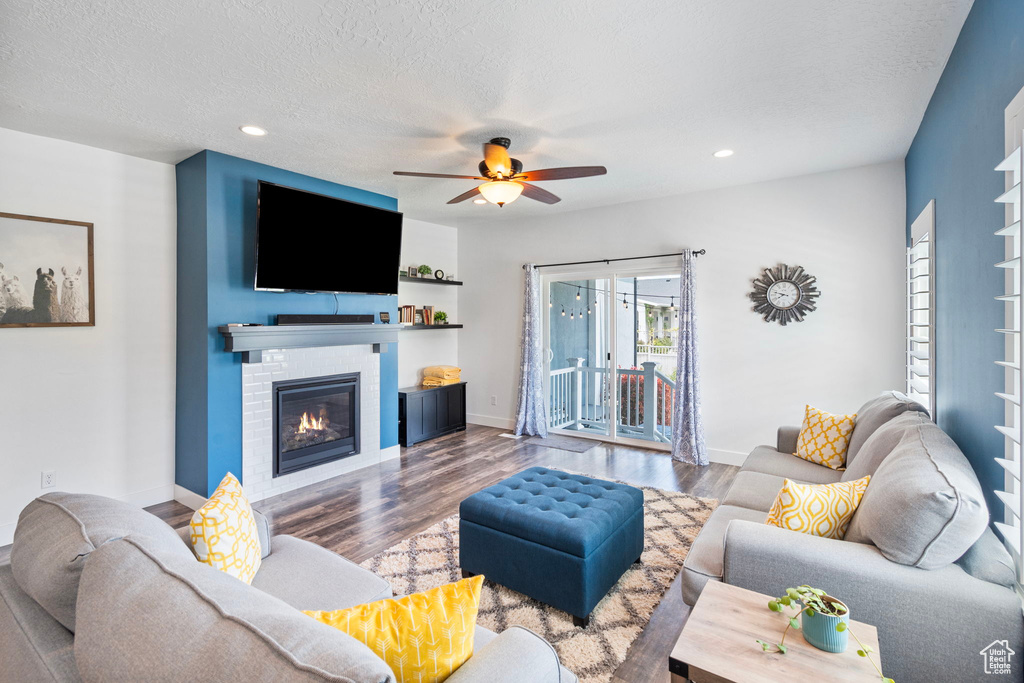 Living room with ceiling fan, hardwood / wood-style flooring, and a textured ceiling