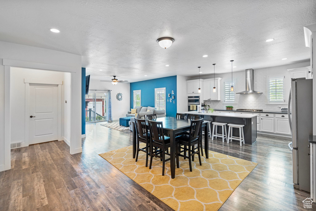 Dining area with dark hardwood / wood-style flooring, ceiling fan, and a textured ceiling