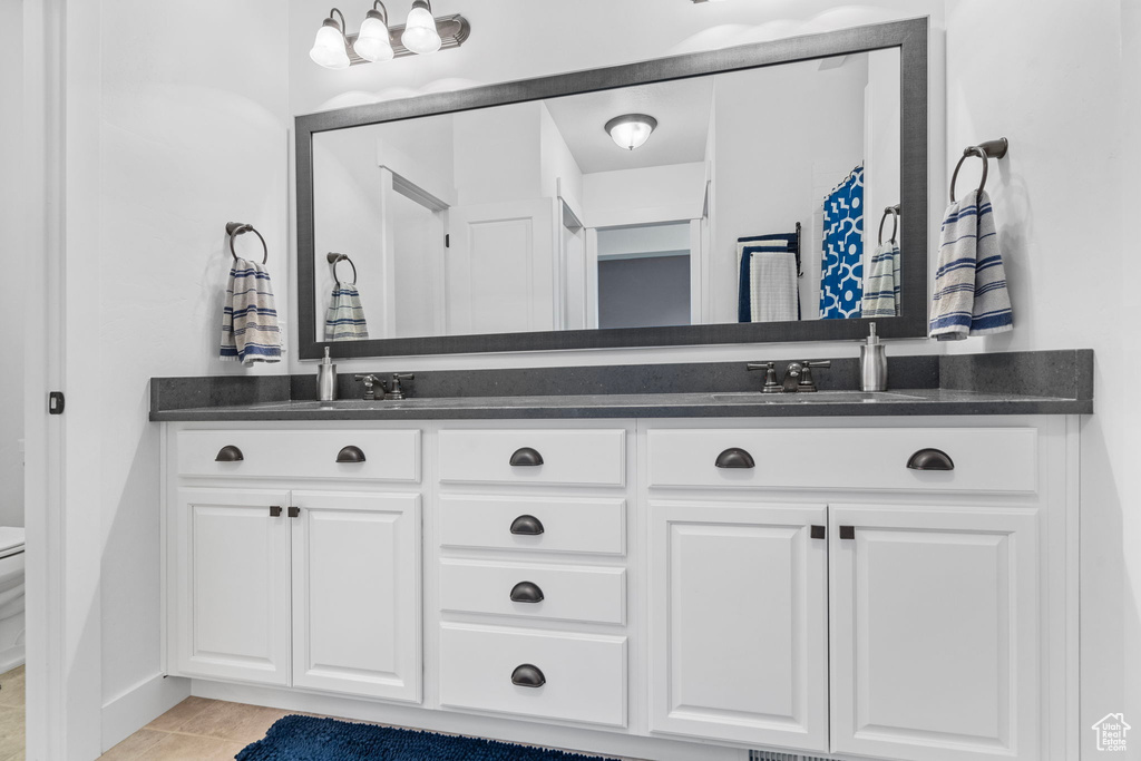 Bathroom with tile floors, toilet, and dual bowl vanity