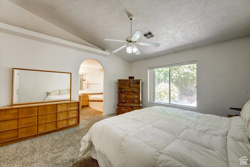 Bedroom featuring ensuite bathroom, ceiling fan, carpet floors, and lofted ceiling