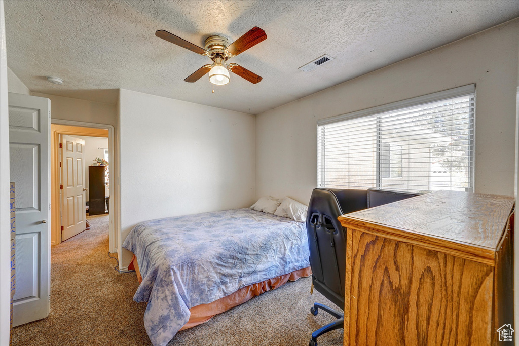 Bedroom with a textured ceiling, ceiling fan, and carpet floors