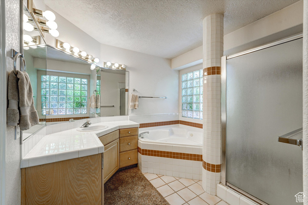 Bathroom with tile floors, separate shower and tub, vanity, and a textured ceiling