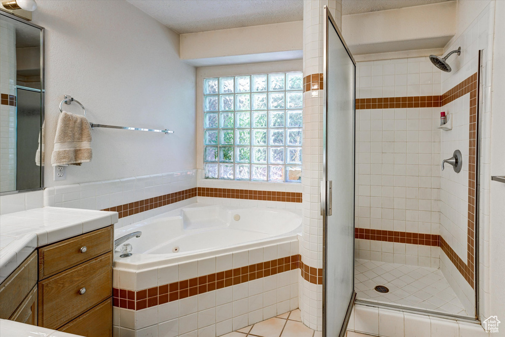 Bathroom featuring tile flooring, shower with separate bathtub, a textured ceiling, and large vanity