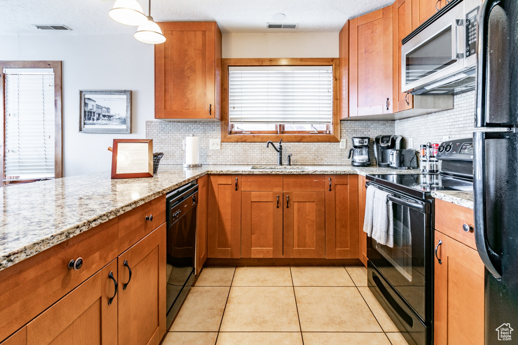 Kitchen featuring black appliances, light stone counters, sink, tasteful backsplash, and light tile floors