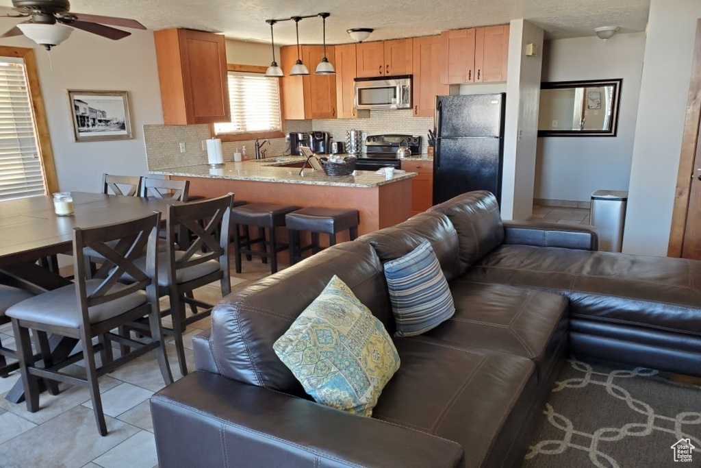 Living room featuring ceiling fan, a textured ceiling, light tile flooring, and sink