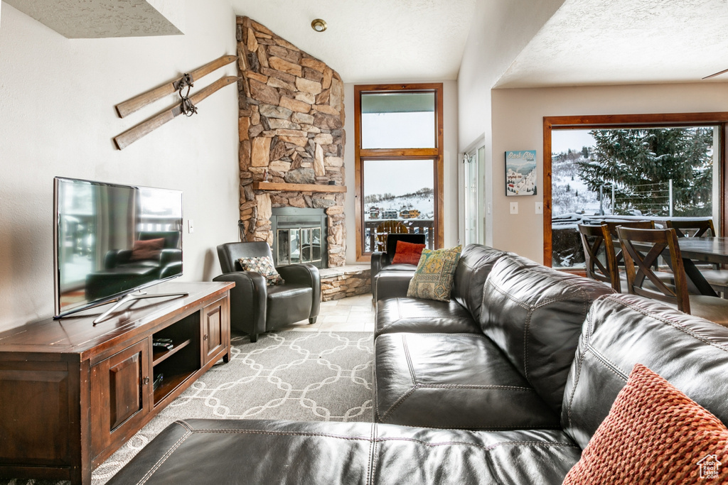 Living room with a textured ceiling, a fireplace, and lofted ceiling