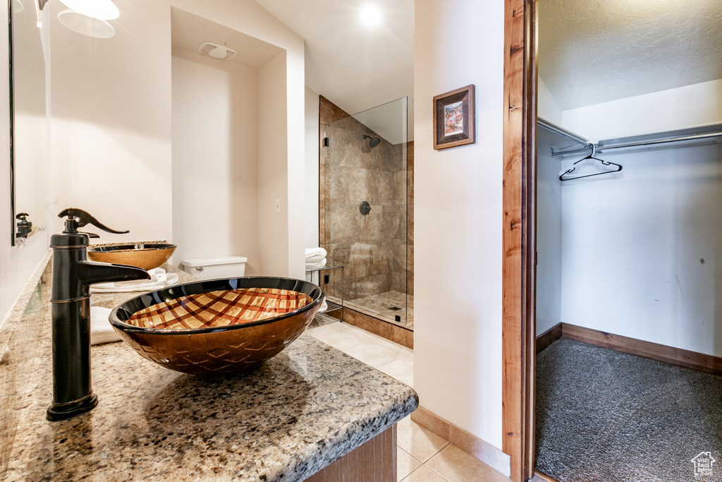 Bathroom featuring a tile shower, tile flooring, and sink