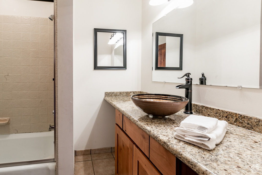 Bathroom with tile floors, tiled shower / bath, and vanity