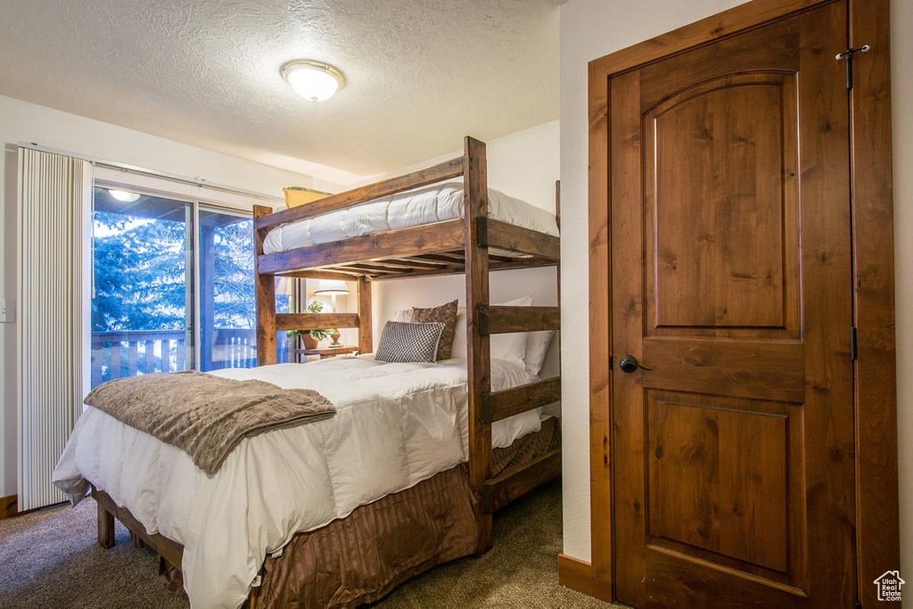 Bedroom featuring access to outside, a textured ceiling, and dark carpet