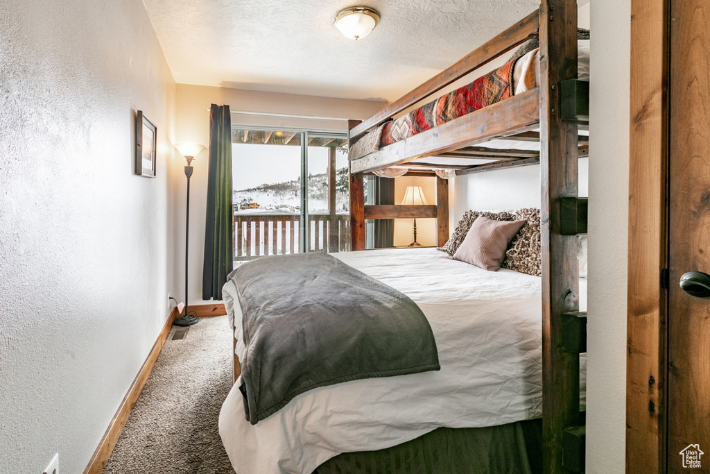 Carpeted bedroom with access to exterior and a textured ceiling