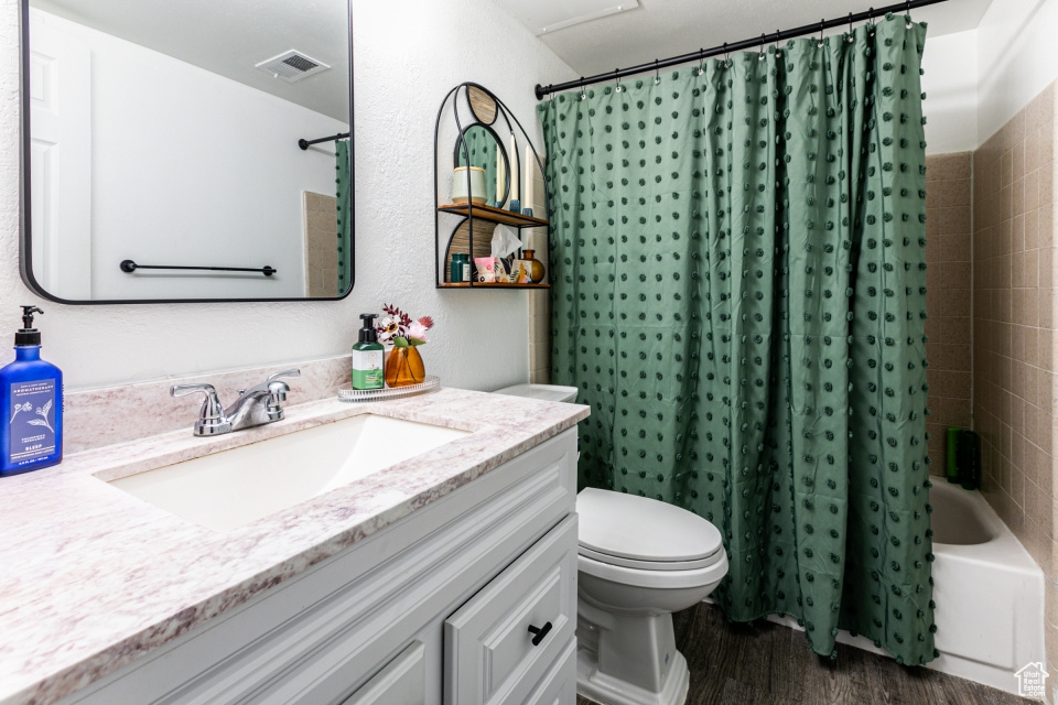 Full bathroom with shower / bathtub combination with curtain, hardwood / wood-style flooring, toilet, and large vanity