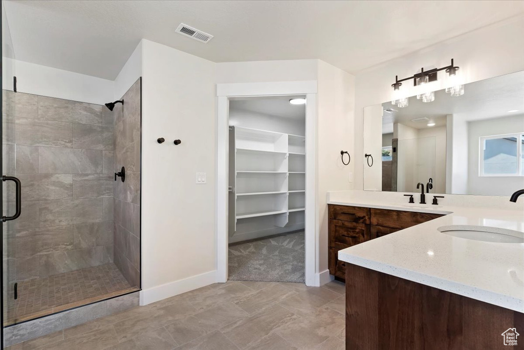 Bathroom with dual bowl vanity, tile patterned flooring, and an enclosed shower