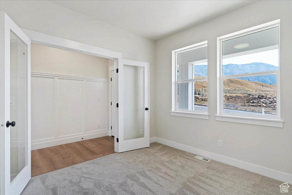 Unfurnished bedroom with french doors, a closet, and light colored carpet