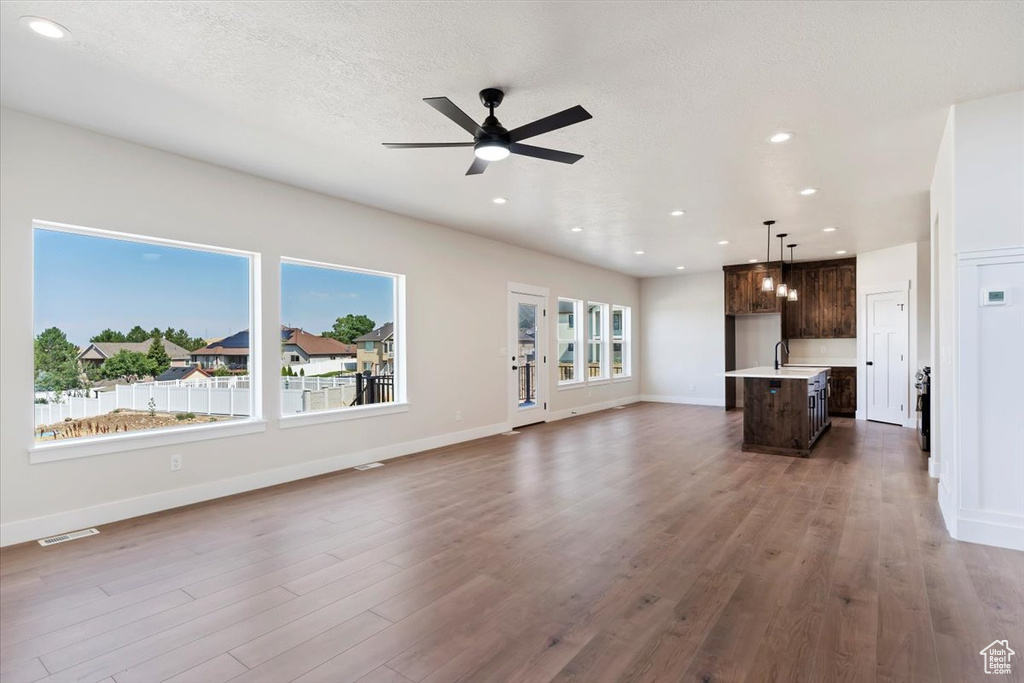 Unfurnished living room featuring ceiling fan, dark hardwood / wood-style floors, a textured ceiling, and sink