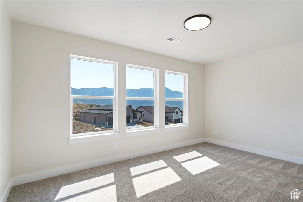 Spare room with a mountain view and light carpet