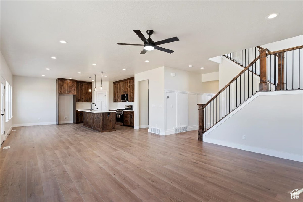 Unfurnished living room with ceiling fan, sink, and light hardwood / wood-style floors