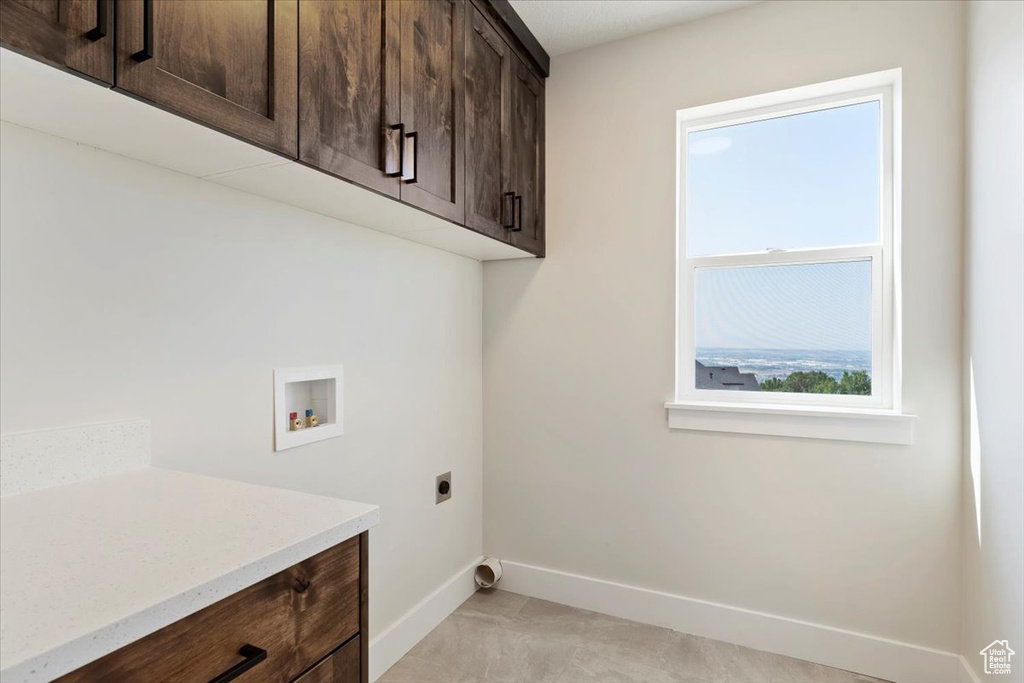 Washroom with electric dryer hookup, light tile patterned flooring, washer hookup, and cabinets