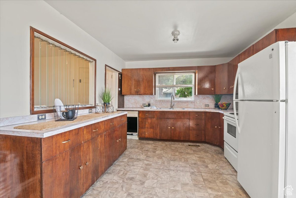 Kitchen with backsplash, sink, white appliances, and light tile floors