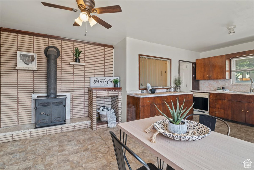 Kitchen with a wood stove, light tile flooring, ceiling fan, tasteful backsplash, and sink