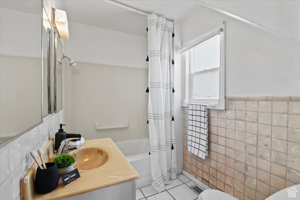 Full bathroom with tile walls, toilet, tile floors, shower / bath combination with curtain, and vanity