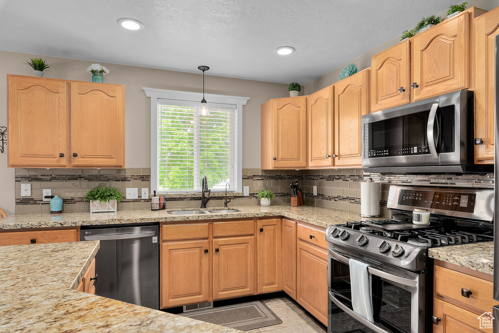 Kitchen featuring decorative light fixtures, sink, tasteful backsplash, and stainless steel appliances