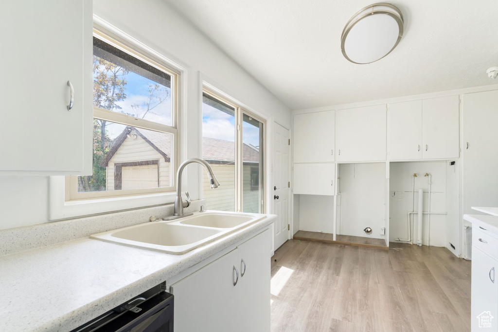 Kitchen featuring white cabinetry, a wealth of natural light, sink, and light wood-type flooring