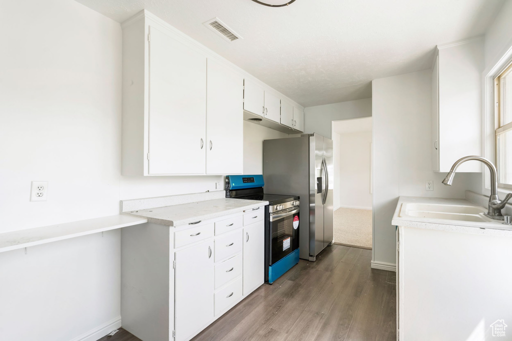 Kitchen featuring sink, white cabinetry, light wood-type flooring, and stainless steel range with electric cooktop