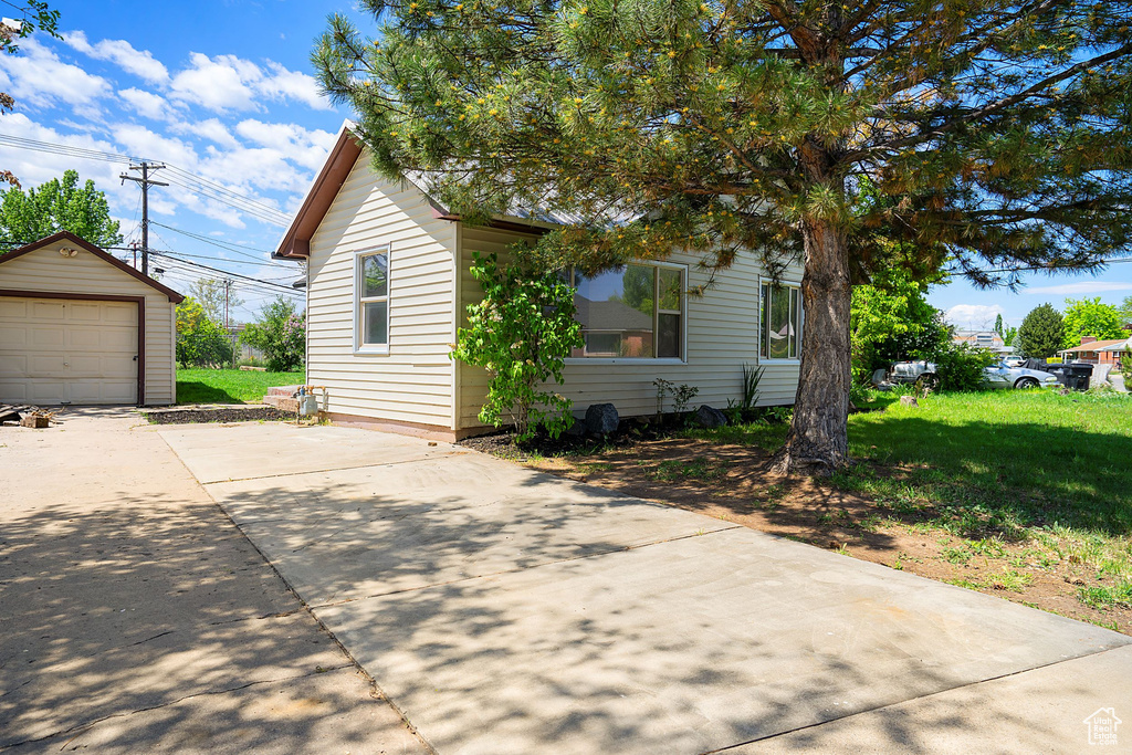 View of front of house with a garage, a front yard, and an outdoor structure