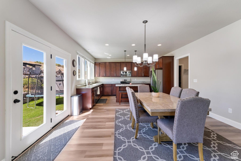 Dining room featuring a notable chandelier, sink, light hardwood / wood-style flooring, and a wealth of natural light