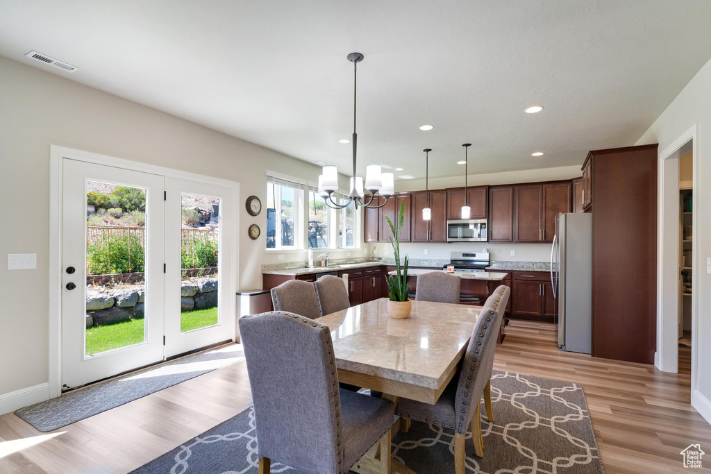 Dining area with an inviting chandelier, plenty of natural light, and light wood-type flooring