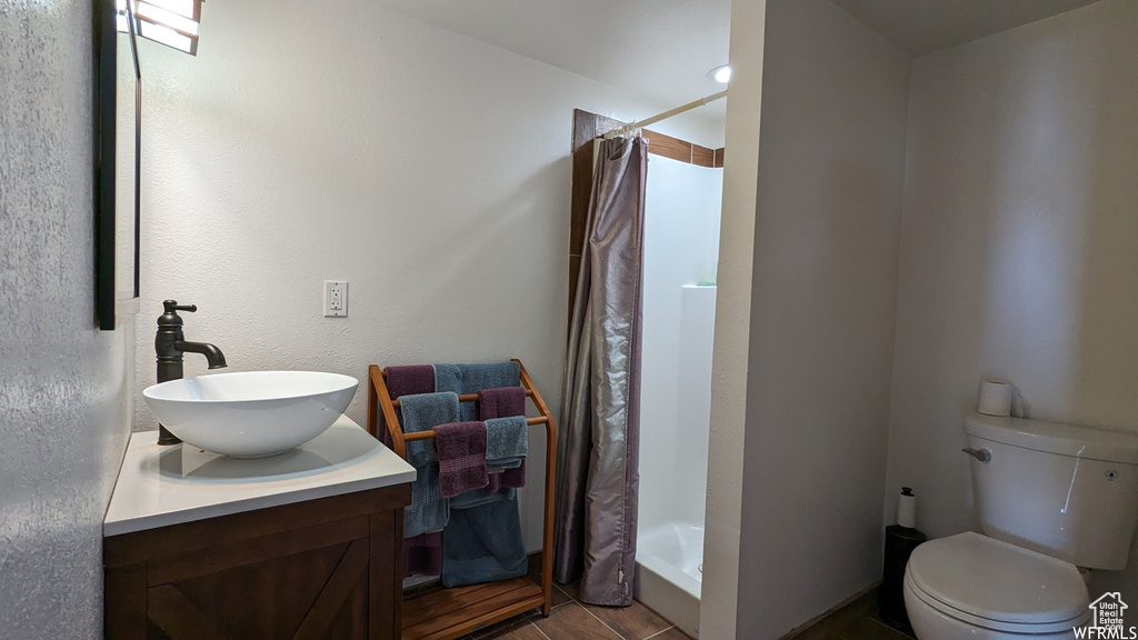 Bathroom featuring a shower with curtain, tile floors, toilet, and vanity