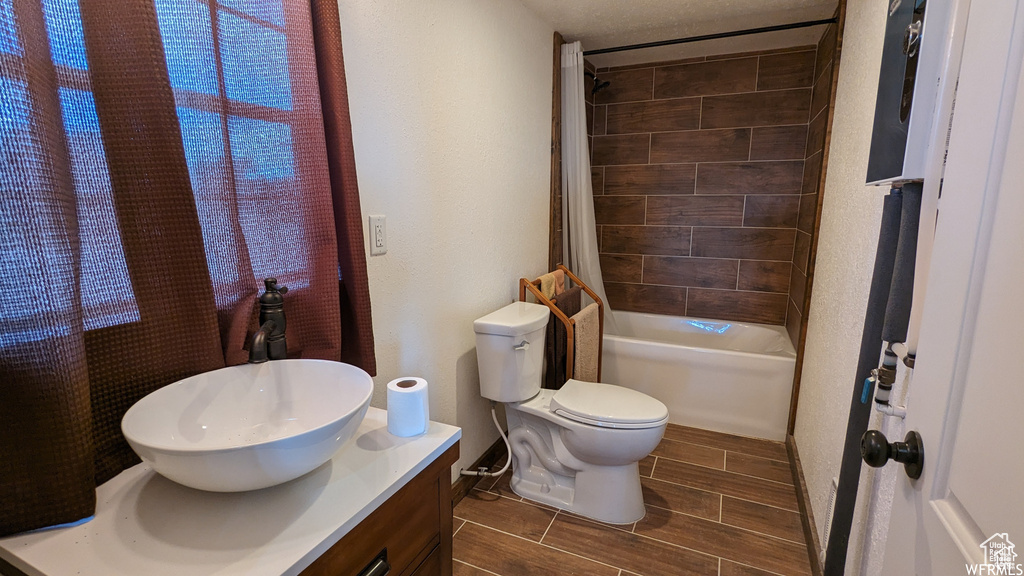 Full bathroom with tile floors, shower / bath combo, vanity, and toilet