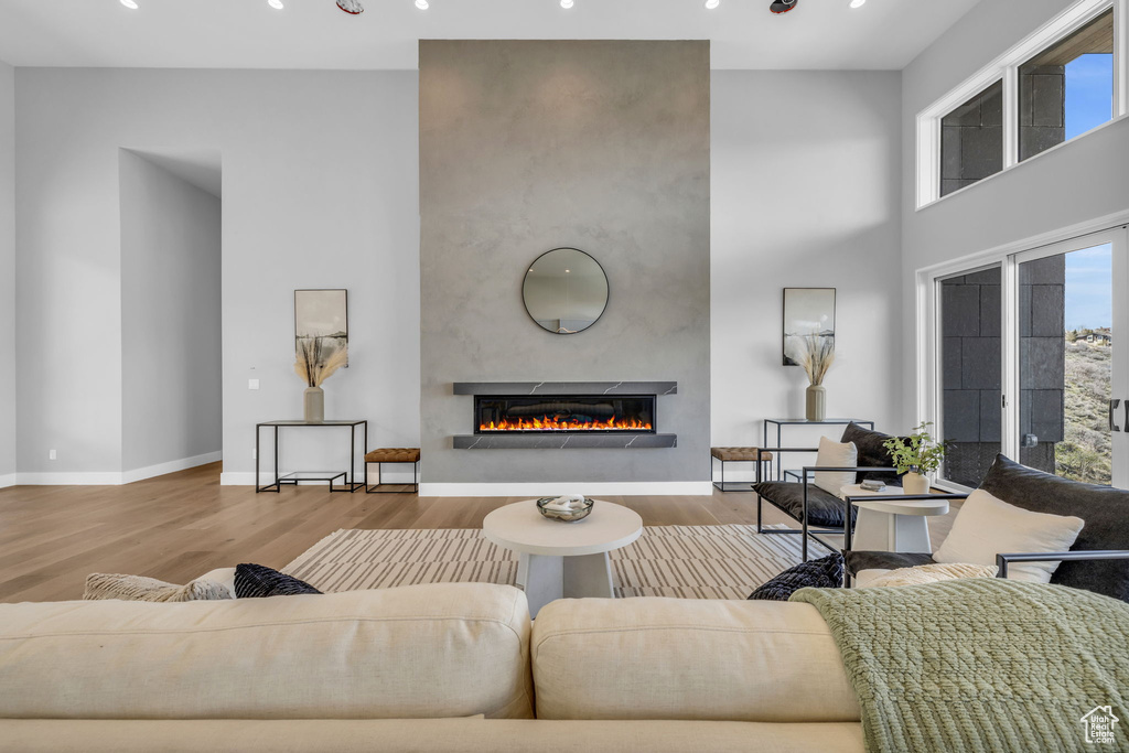 Living room with a large fireplace, wood-type flooring, and a high ceiling