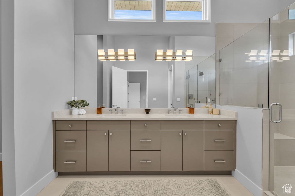 Bathroom featuring a shower with shower door, tile patterned flooring, and double sink vanity