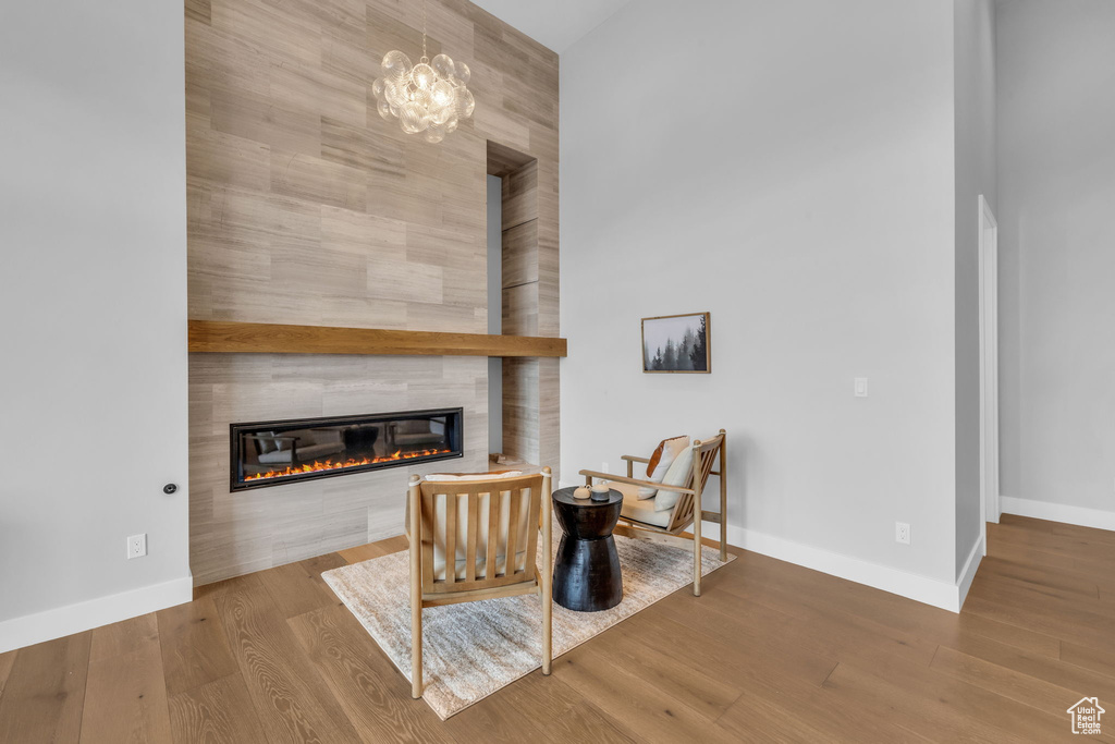 Living room with a chandelier, a fireplace, tile walls, and hardwood / wood-style flooring