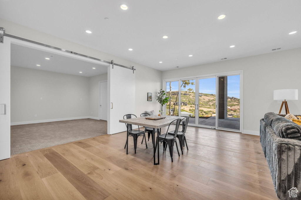 Dining room featuring light colored carpet and a barn door