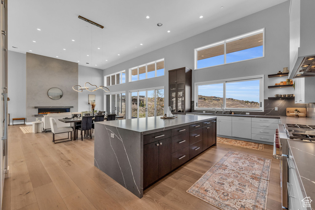 Kitchen with a large fireplace, dark brown cabinets, a kitchen island, and a high ceiling