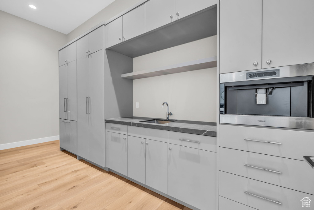 Kitchen featuring light hardwood / wood-style floors, sink, white cabinets, and stainless steel oven