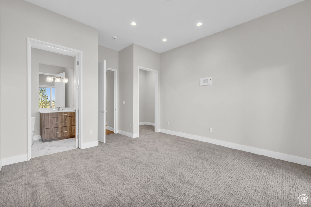 Unfurnished bedroom with ensuite bathroom and light colored carpet